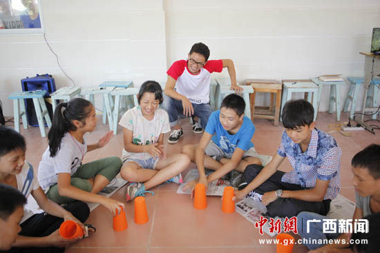 图为大学生志愿者与孩子们一起参与游戏。